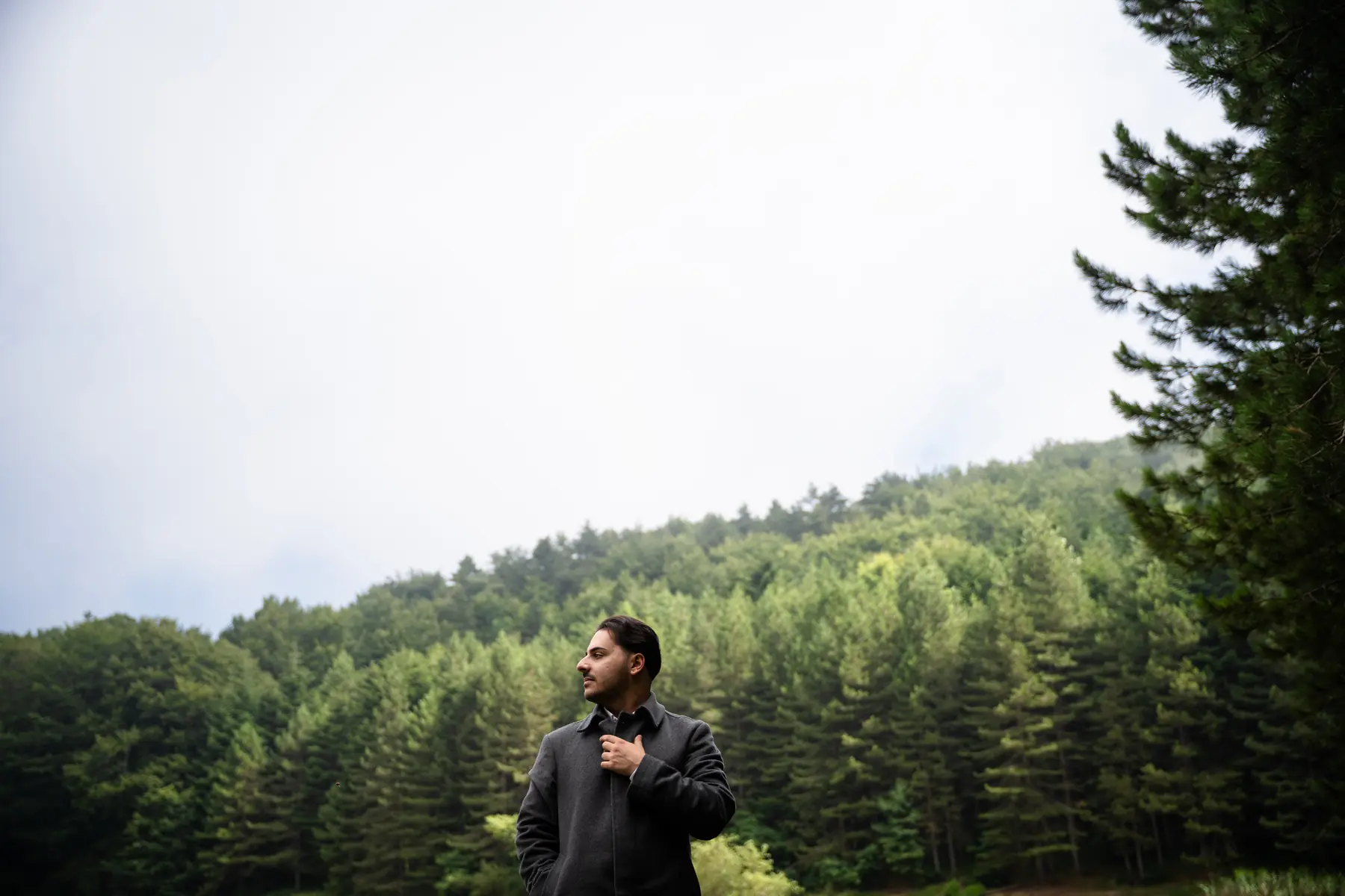 Luigi Gordano in a grey coat among pine trees